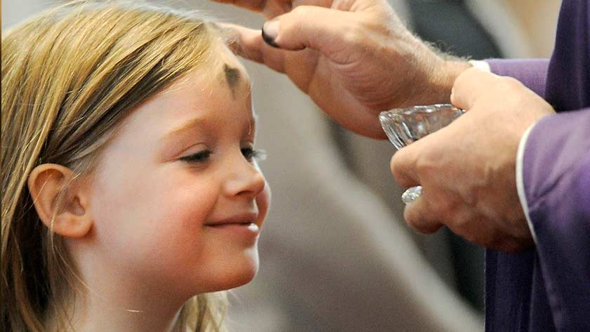 Niña recibiendo las Cenizas en su frente con alegría: Miércoles de Ceniza