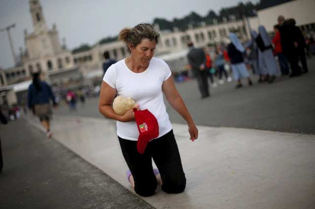 Woman walks on her knees on the way to the Marian shrine of Our Lady of Fatima