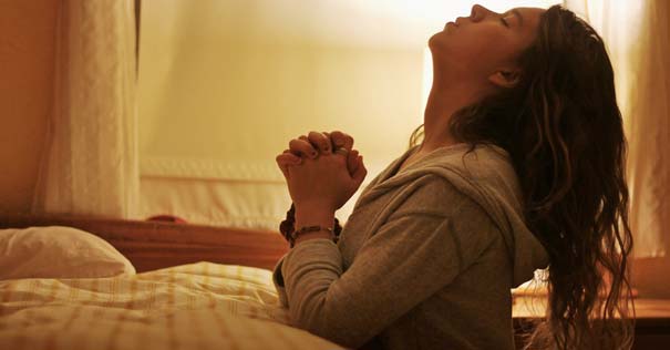 chica joven orando a dios habitacion