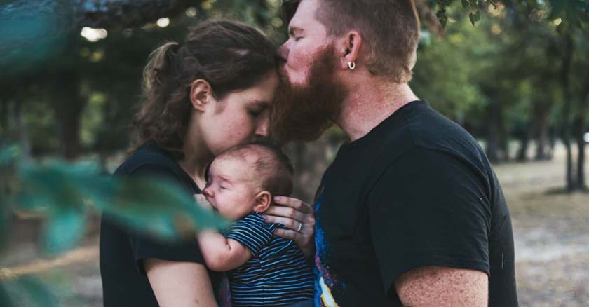 esposos unidos con su bebe juntos abrazados papi besando a mami en la frente