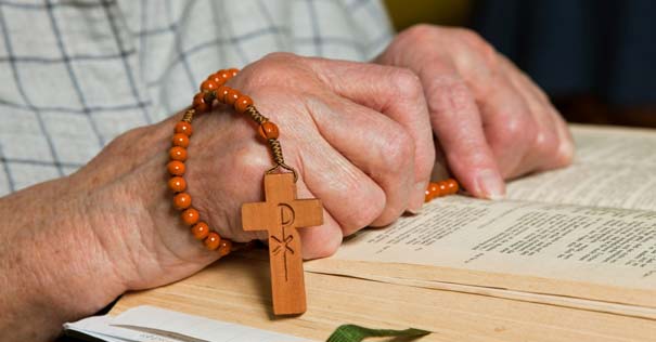 hombre rosario en mano orando con biblia