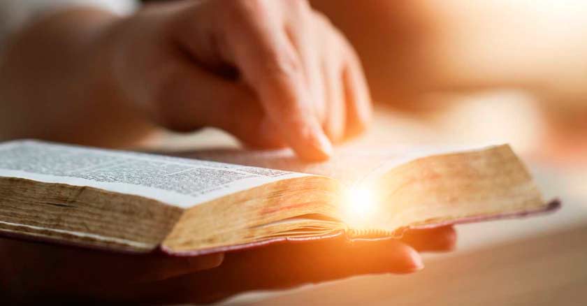 mano de hombre leyendo la biblia reflejo de luz en hojas enemigos del alma