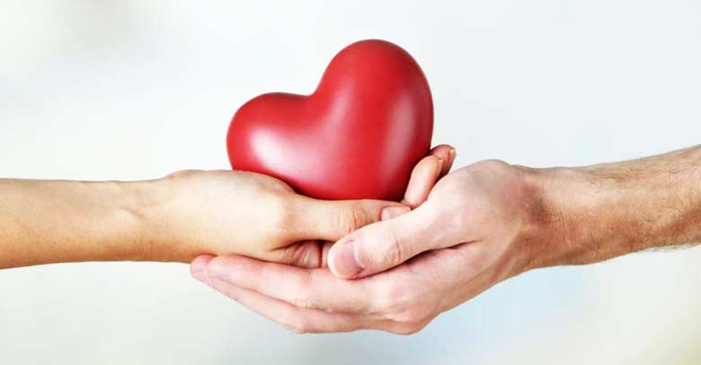 mano de hombre y mujer sosteniendo un corazon rojo