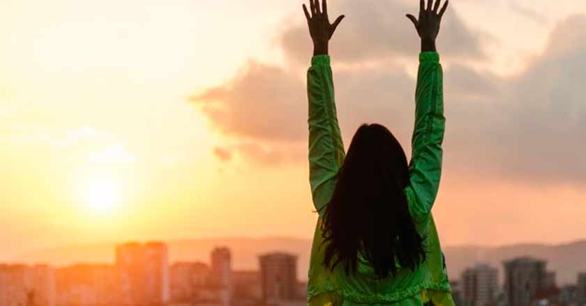 mujer levanta manos feliz actitud enfrentar los retos de la vida