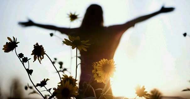 mujer levantando brazos al cielo paz girasol flores 