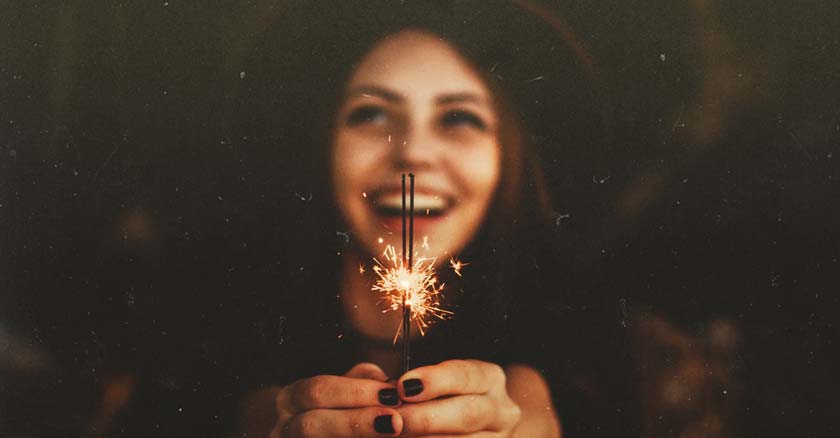 mujer sonriendo con fuego artificial encendido entre sus manos