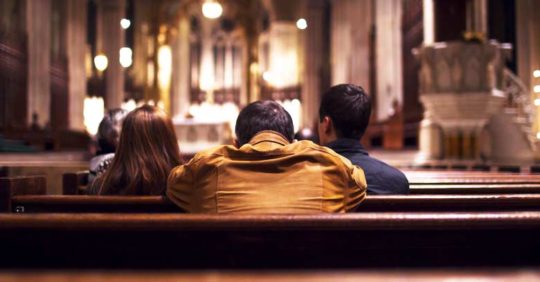 personas sentadas en iglesia catolica orando a dios 