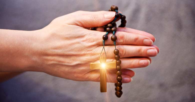 rosario de madera en mano orando
