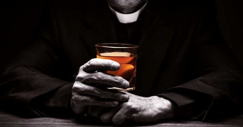 sacerdote con vaso de alcohol en su mano 