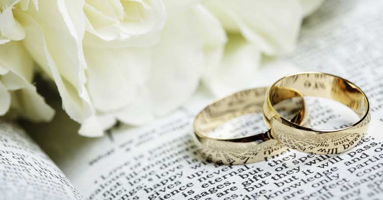 anillos de matrimonio sobre biblia rosas blancas 