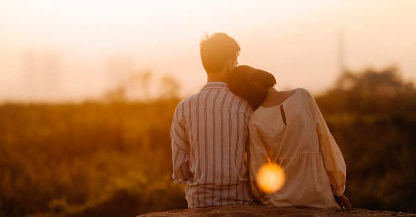 esposa recostada de su esposo sentados mirando atardecerromatico completo