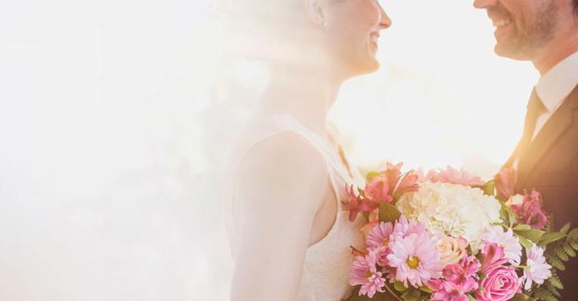 esposos felices recien casados boda matrimonio sostienen buquet de flores luz blanca