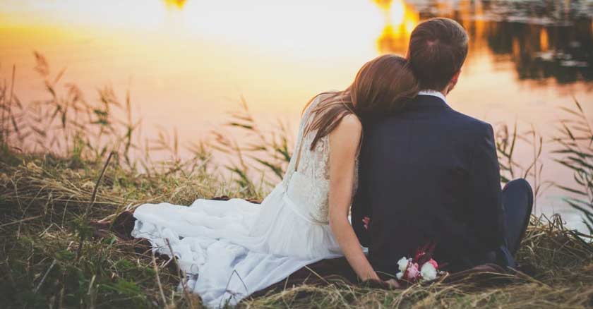 esposos sentados a la orilla de un lago romanticos novia con buquet flores en mano