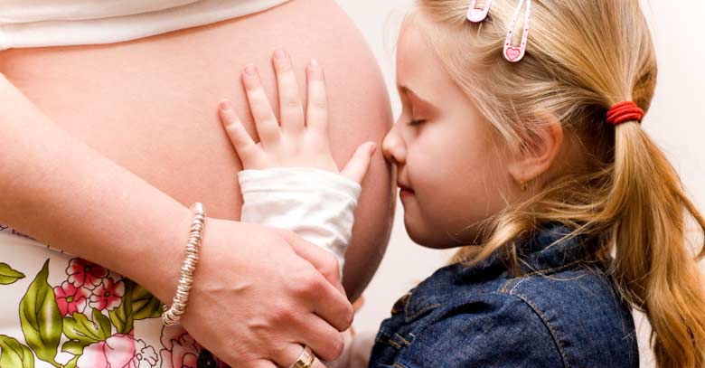 hija rostro frente a barriga de mama embarazada tierna maternidad 