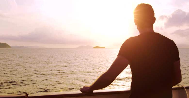 hombre de espalda mirando el mar ocaso sol 