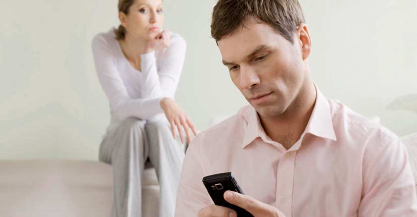 hombre revisando su celular su esposa mujer lo mira con secreto preocupada