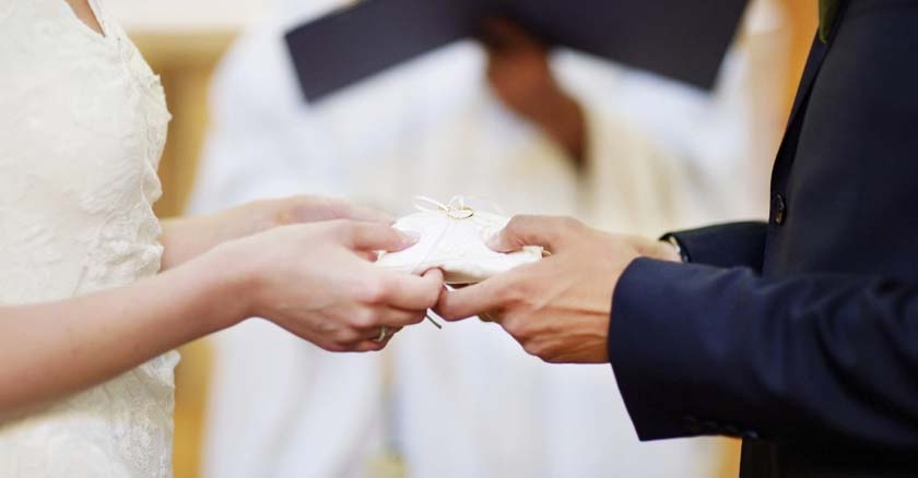 matrimonio catolico pareja de esposos en boda entregando los anillos sobre almohadilla