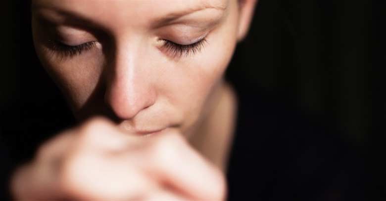 mujer orando con ojos cerrados fondo negro 