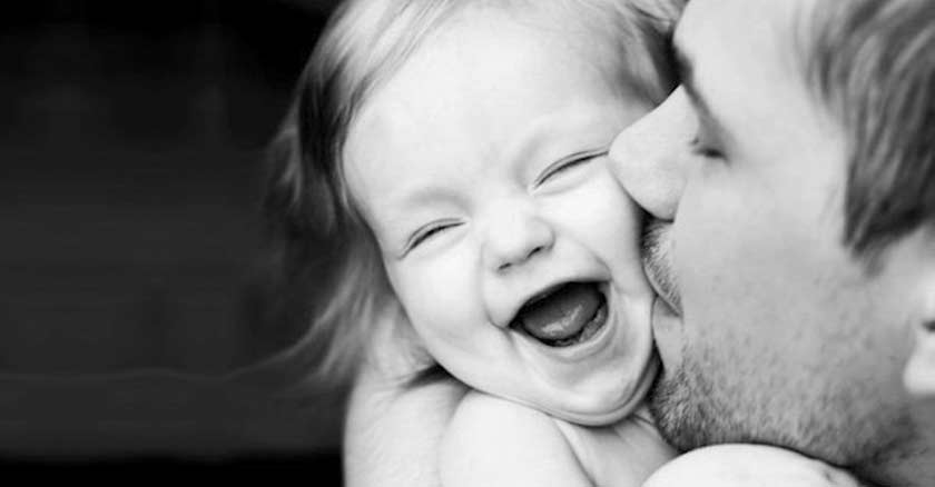padre besando a su hija en la mejilla nina sonriendo blanco y negro