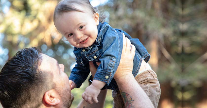 padre levantando a su hijo bebe mientras este sonrie