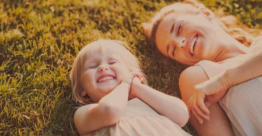 palabras motivadoras para hijos mama y su hija bebe sonriendo recostadas sobre cesped