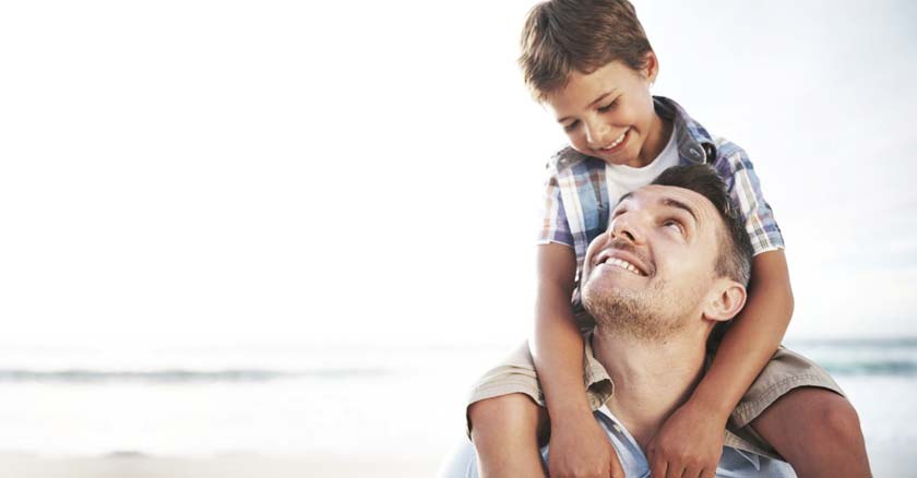 papa cargando a su hijo en su hombre fondo playa