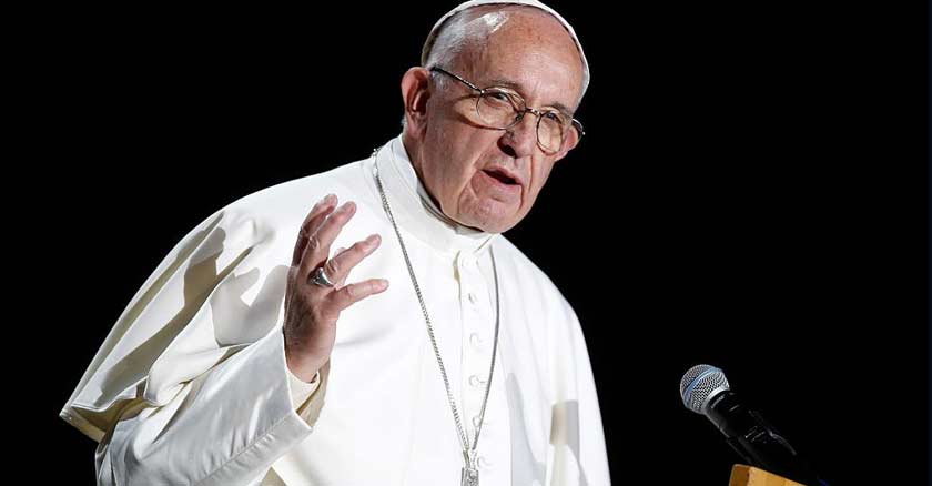 papa francisco hablando frente a microfono con mano levantada fondo negro 