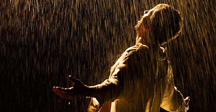 hombre bajo la lluvia abriendo sus brazos reclamando a dios