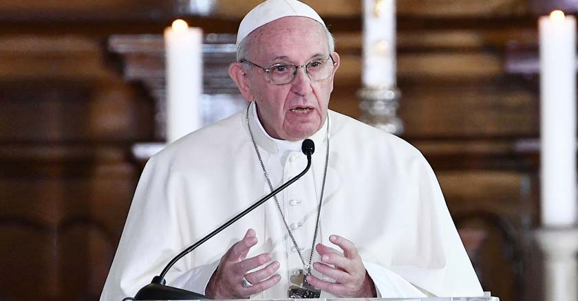 papa francisco hablando desde podio microfonos fondo marron