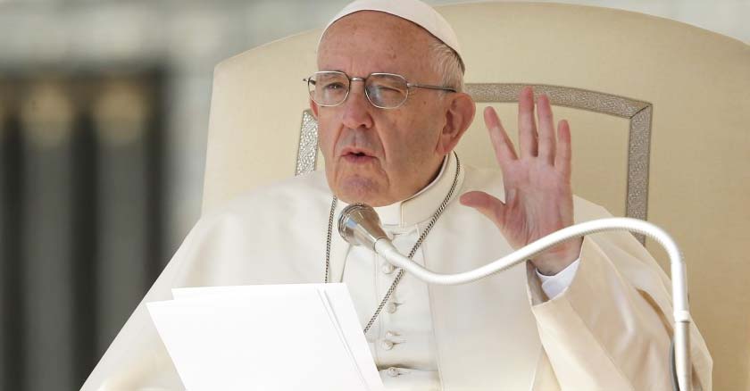 papa francisco sentado en la silla papal vaticano levanta su mano