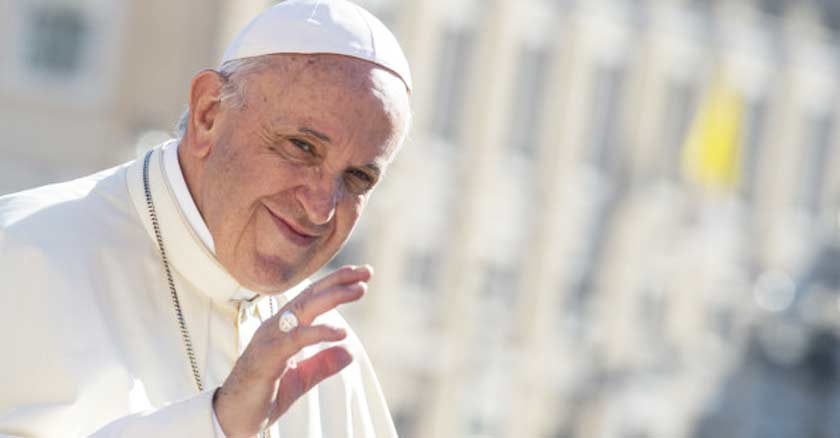 papa francisco sonrie hacia la camara y saluda fondo vaticano