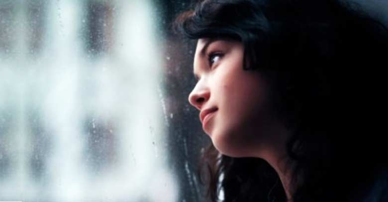 chica mirando por una ventana triste deprimida 