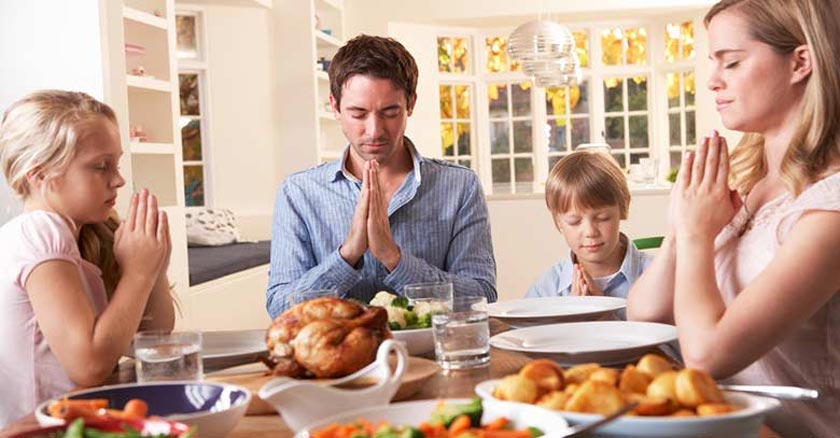 familia reunida en la mesa para comer bendiciendo los alimentos dia 