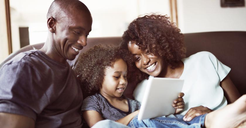 familia sonriente papa mama hija sentados en un mueble disfrutando estar juntos dia