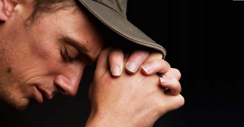 hombre en oracion con gorra fondo negro 