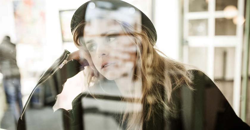 mujer con gorro sentada  mirando por una ventana