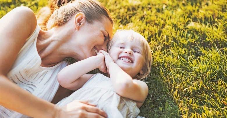 mujer feliz acostada grama con hija sonrie parque