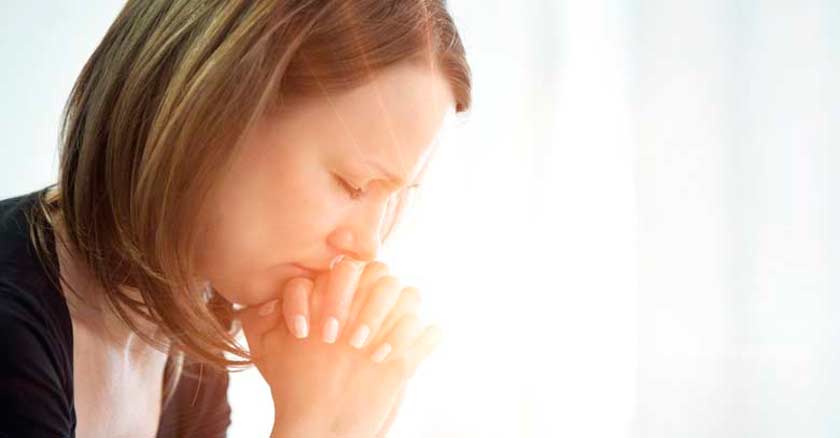 mujer orando en oracion con los ojos cerrados destello de luz
