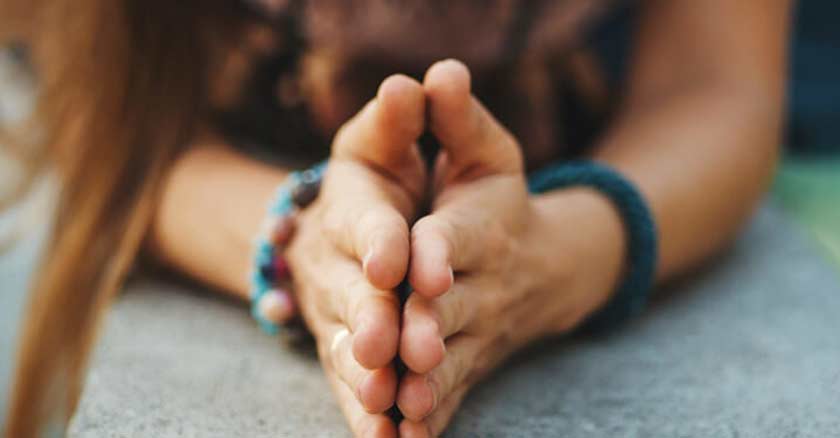 mujer rezando con las manos juntas sobre una mesa en oracion