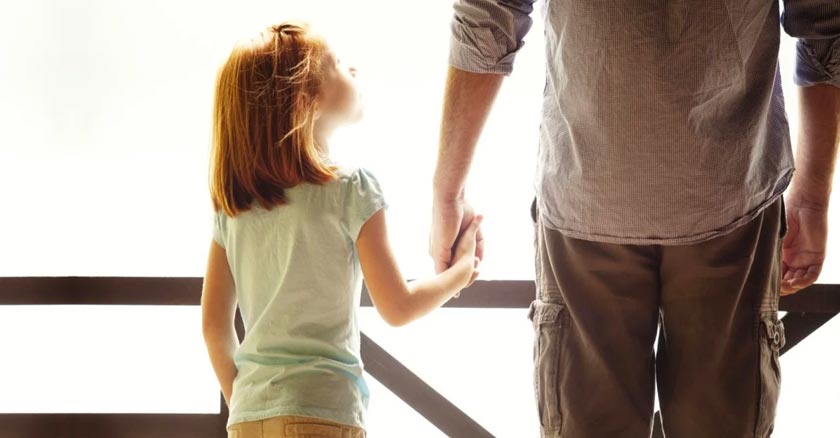 padre sosteniendo la mano de su hija fondo claro dia