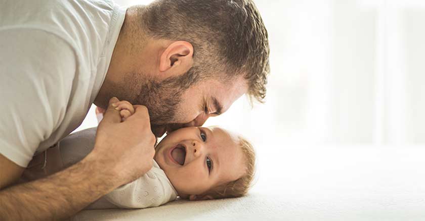 papa bensando a su hijo bebe en el suelo sonrisas fondo claro