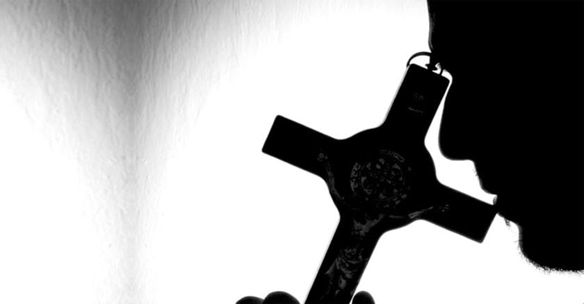 silueta hombre colocando crucifijo sobre su rostro rezando