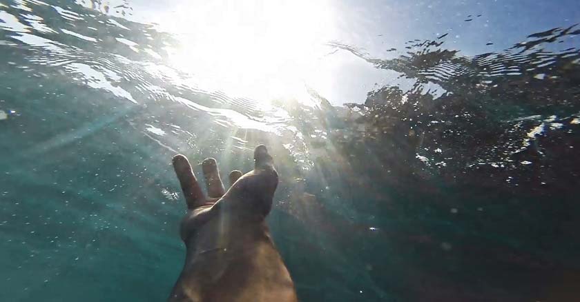 mano de persona bajo el agua intentando pedir ayuda a dios